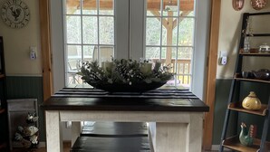 Una mesa de comedor con tapa negra y base blanca, ubicada en una habitación con suelo y techo de madera.