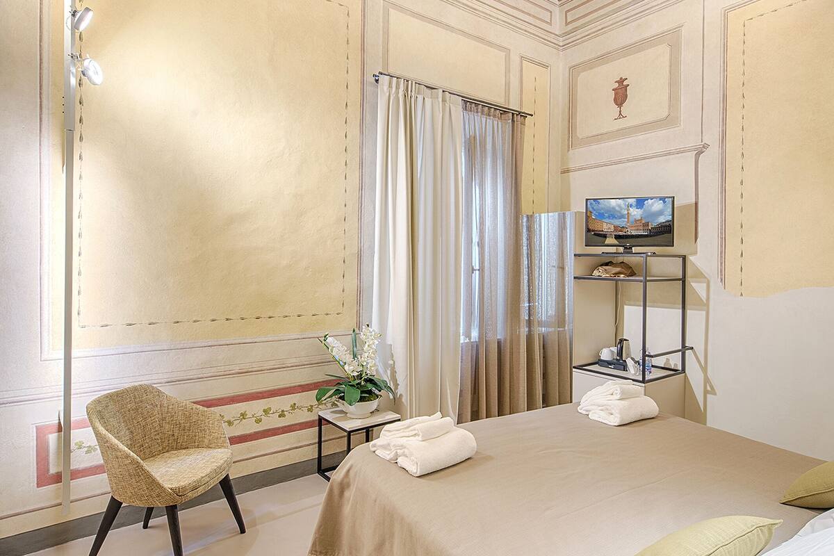 Een hotelkamer met een bed, stoel, televisie en bureau.