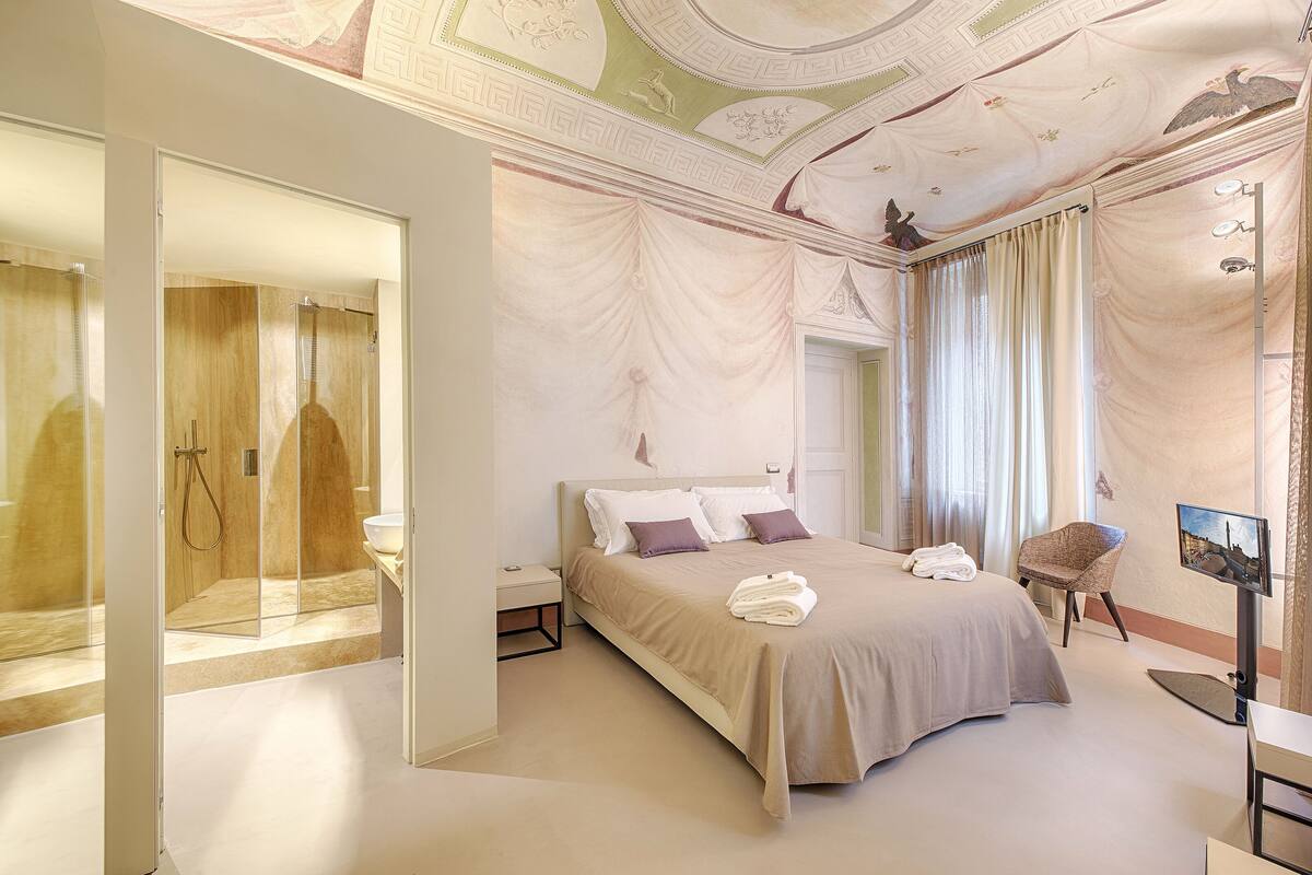 Een moderne hotelkamer met een groot bed, een televisie en een douchecabine met glazen wanden.