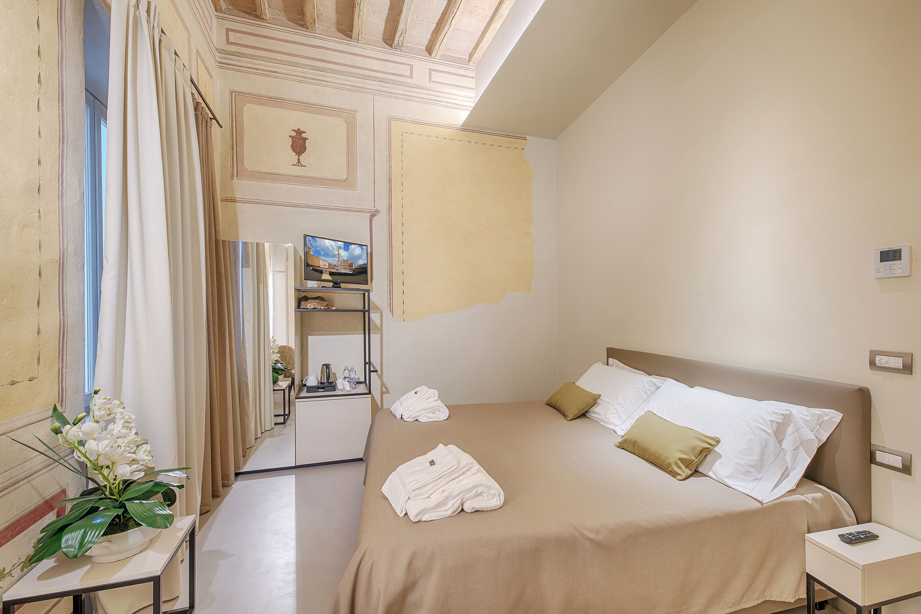Ein Hotelzimmer mit Bett, Nachttisch, Fernseher und einem durchgegangenen Tür sichtbaren Badezimmer.