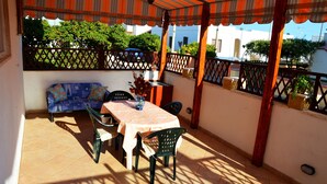 A covered patio area with a table and chairs, a sofa, and a potted plant.