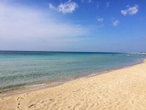 Een strand met helder turquoise water en een zandstrand.