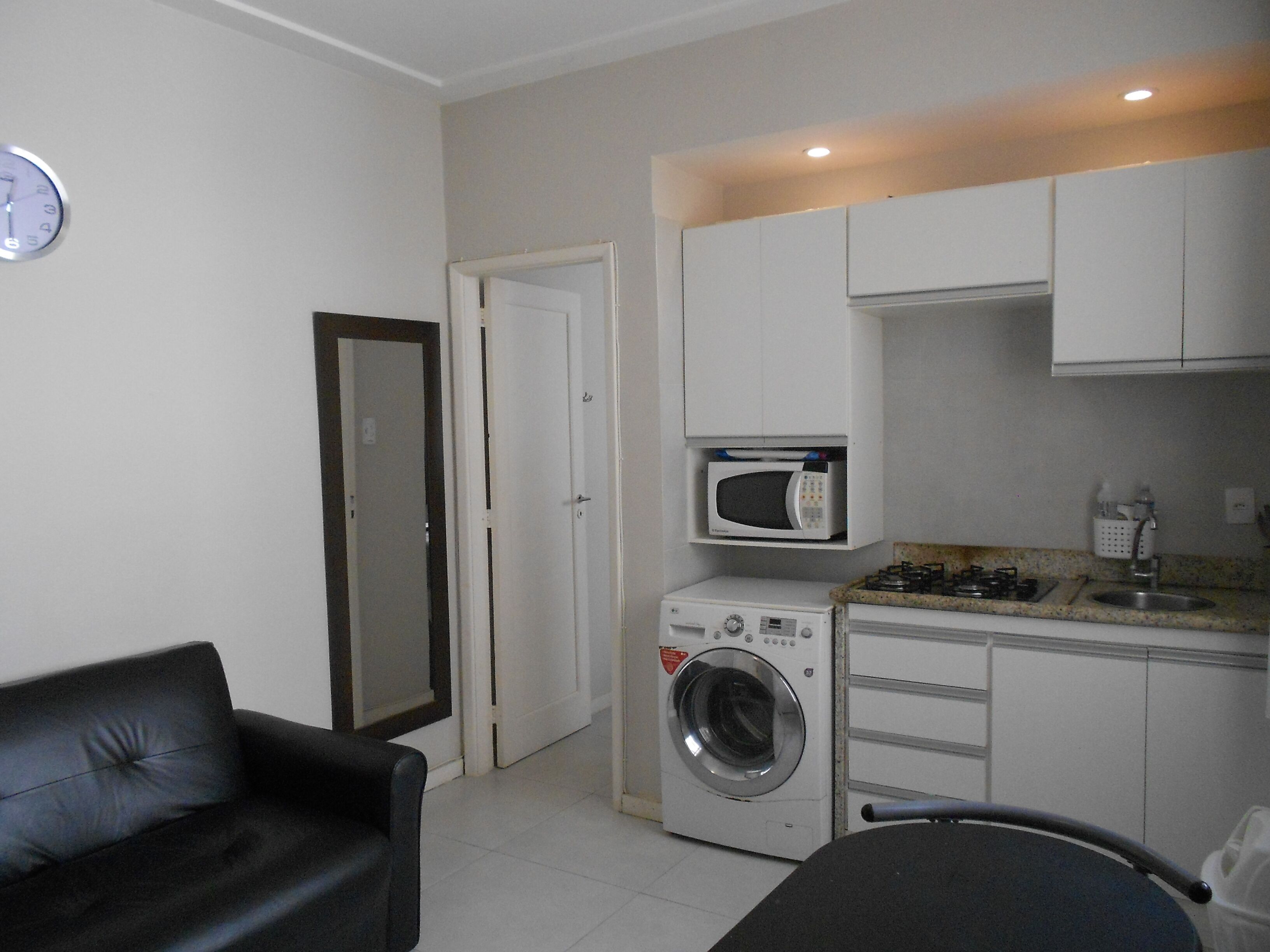 A compact kitchen with a washing machine, microwave, and gas stove.