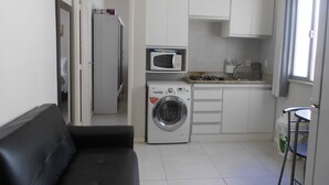 A compact living space with a washing machine, a microwave, and a kitchenette. - Gohouse - Nabuco 604 (Rio de Janeiro)