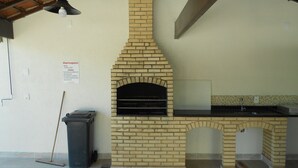 Una cocina con un horno de ladrillo, un fregadero y una escoba apoyada en la pared.