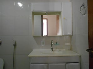 A bathroom with a white sink, mirror, and towel rack.