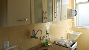 Una cocina con armarios color beige, un microondas, un fregadero y una estufa a gas.