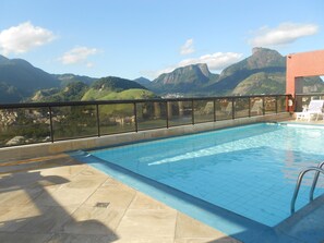 Una piscina con vistas a montañas y un paisaje urbano.