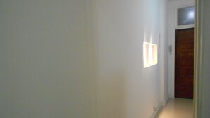 A narrow hallway with white walls and a wooden door at the end. - Gohouse - Riachuelo 306 B (Rio de Janeiro)