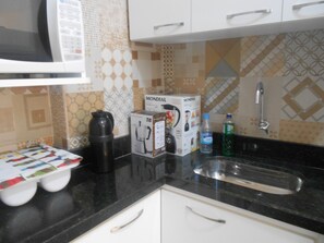 Eine Küche mit Kaffeemaschine, einer Kiste, einer Wasserflasche und einem Spülbecken.