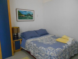 A bedroom with a bed, a chair, a lamp, and a framed picture on the wall. - Gohouse - Piragibe 203 (Rio de Janeiro)
