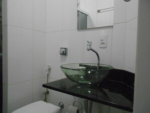 A modern bathroom with a glass bowl sink, a handheld showerhead, and a toilet. - Gohouse - Piragibe 203 (Rio de Janeiro)