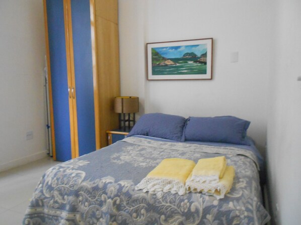A bedroom with a bed, a nightstand, a lamp, and a framed picture on the wall. - Gohouse - Piragibe 203 (Rio de Janeiro)