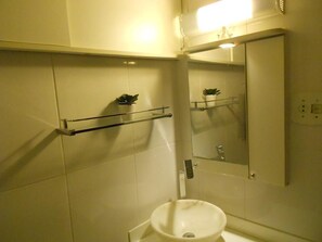 A bathroom with a white sink, a mirror, and a shelf with a potted plant. - Gohouse - Siqueira 1037 (Rio de Janeiro)