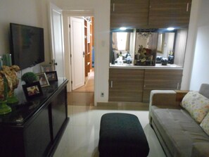 A living room with a sofa, a television, and a dining area with a table and chairs. - Gohouse - Visconde 201 B (Rio de Janeiro)