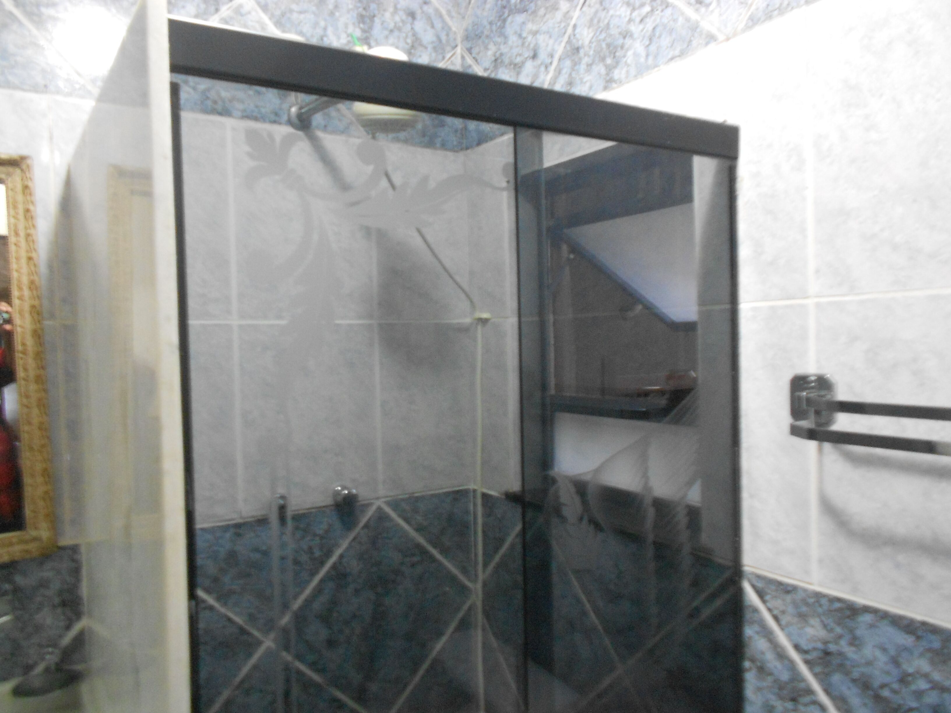 Un baño con cabina de ducha de vidrio, un perchero y un espejo.