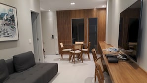 A modern living room with a grey sofa, wooden dining table, and chairs. - Gohouse - Ataulfo 201 (Rio de Janeiro)