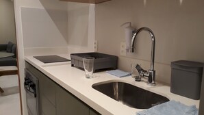 A modern kitchen with a stainless steel sink, a built-in dishwasher, a grey countertop, and a blue towel. - Gohouse - Ataulfo 201 (Rio de Janeiro)