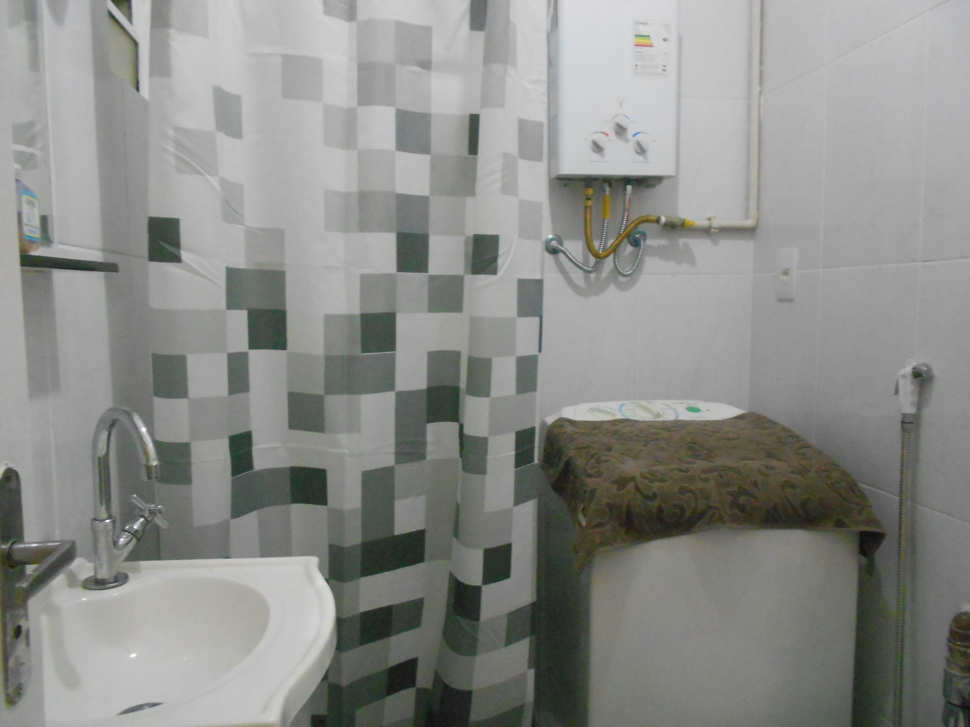Une salle de bain avec un rideau de douche à carreaux, un lavabo, des toilettes et un radiateur fixé au mur.