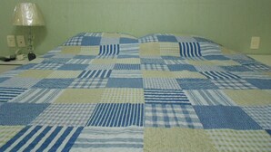 A bed with a checkered quilt, a bedside lamp, and a wall socket. - Gohouse - Visconde 402 B (Rio de Janeiro)