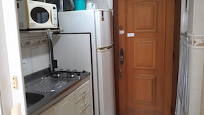 A compact kitchen with a stove, microwave, and refrigerator. - Gohouse - Siqueira 1417 (Rio de Janeiro)