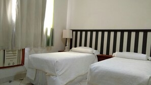 A hotel room with two single beds, a bedside table with a lamp, and a large mirror on the wall. - Gohouse - Siqueira 1417 (Rio de Janeiro)