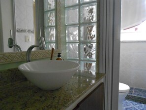 A bathroom with a white sink, a mirror, and a window with a grid pattern. - Gohouse - Ferreira 76 (Rio de Janeiro)