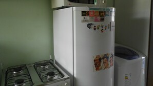 A kitchen with a white refrigerator, a microwave, and a gas stove. - Gohouse - Ferreira 76 (Rio de Janeiro)