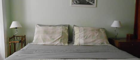A bedroom with a bed, two bedside lamps, and two framed pictures on the wall.
