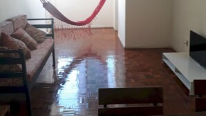 Un salon avec un hamac, un canapé, un meuble pour la télévision et un plancher en bois.
