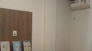 Ein Schlafzimmer mit einem hölzernen Kopfteil, einem weißen Bett und einem Regal mit drei Büchern.
