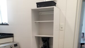 Ein kleiner Waschbereich mit Waschmaschine, Wäscheständer und einem Tisch mit Stuhl.