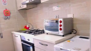 A compact kitchen with a microwave, stove, oven, and a small refrigerator. - Cozy Rooms Rome (Rome)