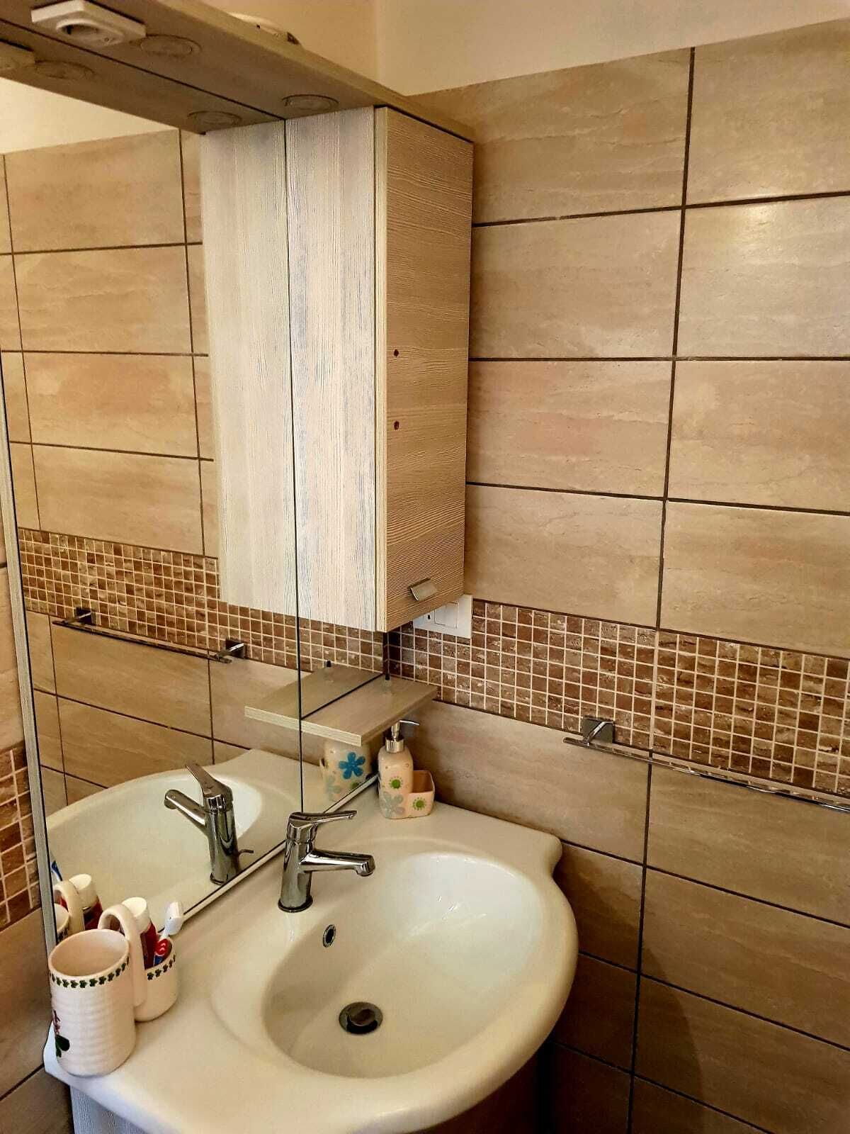 A bathroom with a white sink, a mirror, and a tiled backsplash.