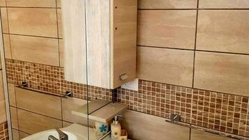 A bathroom with a white sink, a mirror, and a tiled backsplash.