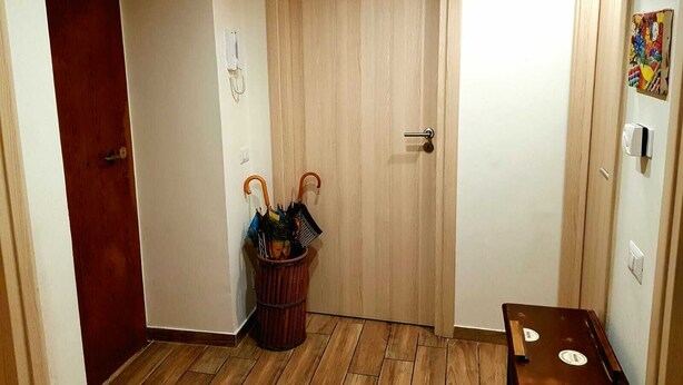 A hallway with a wooden door, a wall-mounted telephone, and a wicker basket with umbrellas. - Cozy Rooms Rome (Rome)