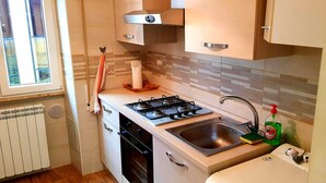 A compact kitchen with a gas stove, sink, and a built-in oven. - Cozy Rooms Rome (Rome)
