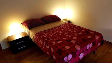 Ein Bett mit einer rot gepunkteten Decke, zwei Kissen und zwei Nachttische mit Lampen.