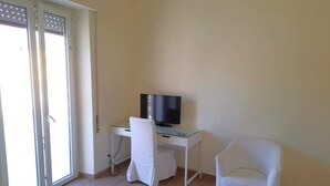A room with a bed, a desk with a computer, a chair, and a television. - Cozy Rooms Rome (Rome)