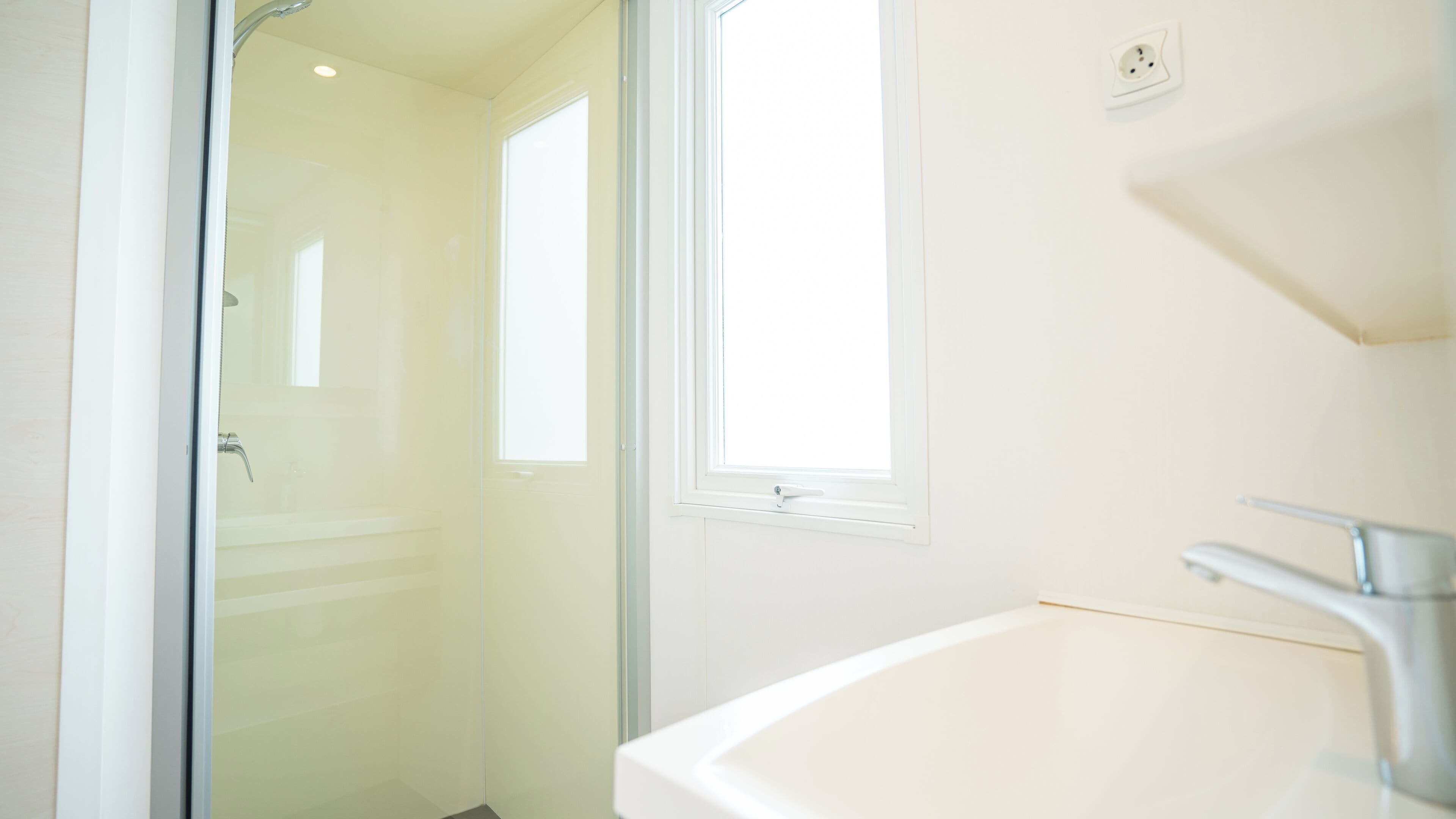 A bathroom with a white sink, a mirror, and a shower area.