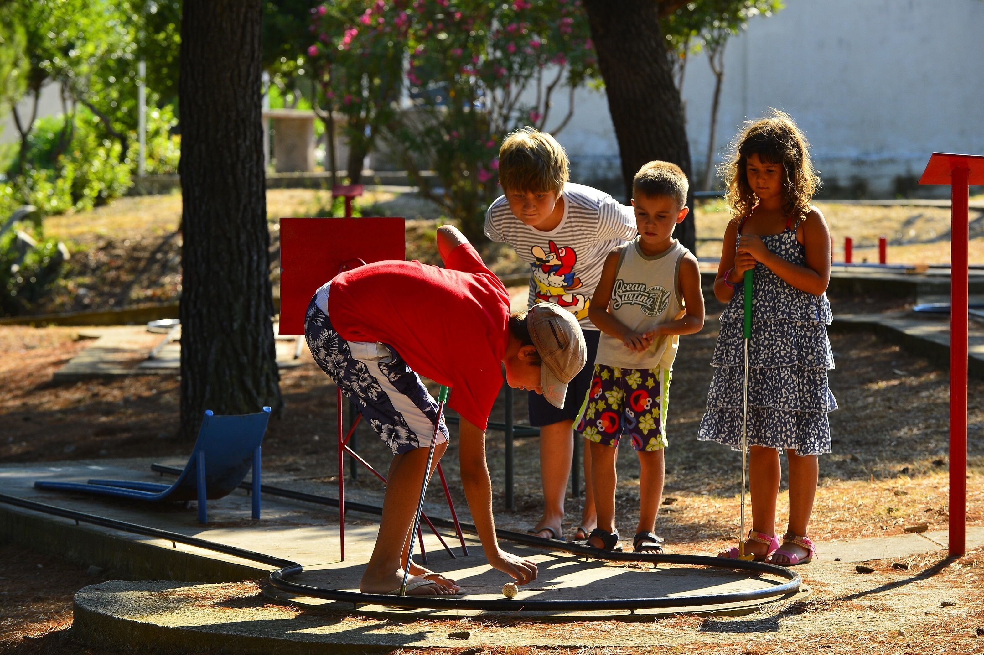 Un grupo de niños jugando en un parque con un balancín y un tobogán.