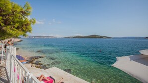 A clear coastal view with a beach, rocky shoreline, and a distant island. - Happy Camp in Amadria Park Camping Trogir (Seget)