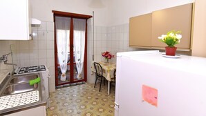 A compact kitchen with a gas stove, sink, and a dining area with a table and chairs. - Tiberius Suite Roma (Rome)