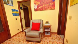 A room with a patterned floor, a leather armchair with a red cushion, and a small wooden side table with a decorative item. - Tiberius Suite Roma (Rome)