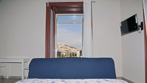 A room with a bed, a desk, and a TV mounted on the wall. - Sun&TheCity (Naples)