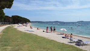 Ein Strand mit Menschen, die sich sonnen, schwimmen und am Ufer entlanggehen.
