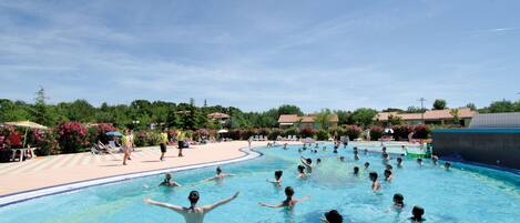 Een seizoensgebonden buitenzwembad, ligstoelen bij het zwembad