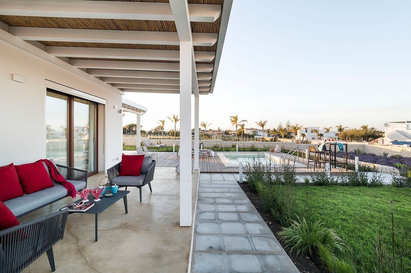 A covered outdoor area with a pool, seating, and a view of the surrounding landscape.