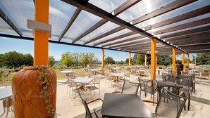 An outdoor patio area with tables and chairs, a large decorative vase, and a clear view of the surrounding landscape. - Happy Camp in Camping Park Umag (Karigador)