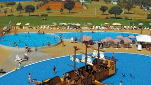 A large outdoor swimming pool with a pirate ship centerpiece, surrounded by lounge chairs and umbrellas. - Happy Camp in Camping Park Umag (Karigador)
